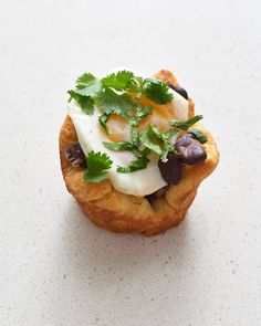 an appetizer with olives, cheese and cilantro on top sits on a white surface