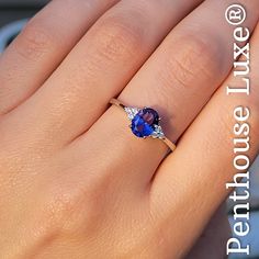 a woman's hand with a ring on it and an oval blue stone in the middle