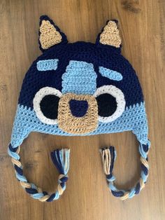 a crocheted hat with a bear's face on it sitting on top of a wooden floor