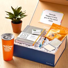 a welcome gift box with an orange drink and some personal care items on the table