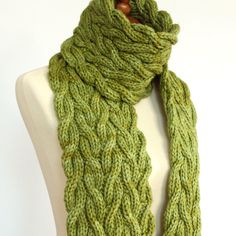 a green knitted scarf sitting on top of a mannequin