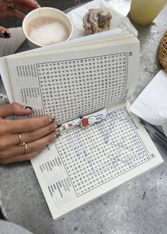 a person sitting at a table with an open book and crossword puzzle on it