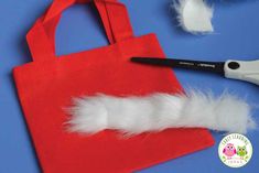 a red bag with white feathers on it and scissors to cut out the feather for an ornament