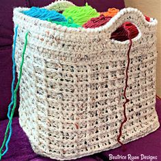 a crocheted basket with yarn in it on a purple couch next to a wall