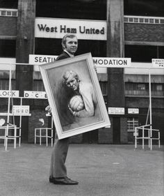 a man holding up a painting in front of a building