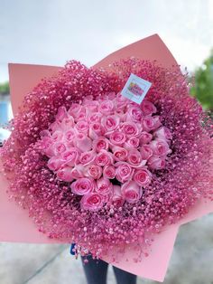 a bouquet of pink roses is wrapped in pink paper and surrounded by baby's breath