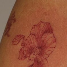 a close up of a tattoo on the back of a woman's shoulder with a flower