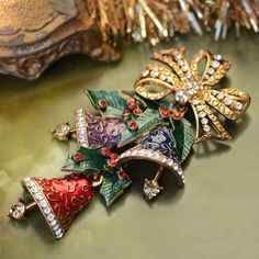 "During the 1940s, wearing a Christmas pin or corsage became a tradition of the season. I designed the Enamel Christmas Bells Pin with hidden joints to allow the bells and clappers to move independently, gently swinging from the crystal bow. Enameled in translucent royal blue, purple and crimson, each bell has a raised design and is edged in premium diamante crystal. The clappers tinkle merrily, set with large champagne color crystals. Blended blue-green enamel holly leaves are set with bright r Christmas Brooches, Christmas Bling, Tacky Christmas, Jewelry Christmas Tree, Holiday Pins, Holly Leaves, Pretty Christmas, Sweet Romance, Christmas Pins