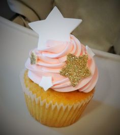 a cupcake with pink frosting and gold sprinkles on the top