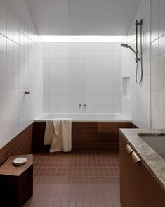 a bathroom with brown and white tile flooring next to a bathtub, toilet and sink