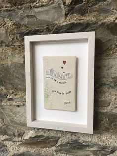 a white frame holding a piece of paper with writing on it and a red heart