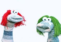 two knitted animals with green hair and red eyes standing next to each other in front of a white wall