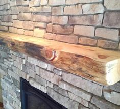 a fire place with a wooden shelf above it