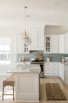 a kitchen with white cabinets and an island in the middle, along with two stools