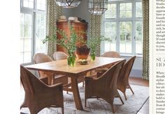 a dining room table and chairs in front of large windows with green draperies on them