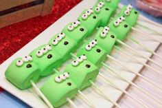 there are many green cake sticks with eyes on them sitting on a table next to other food items