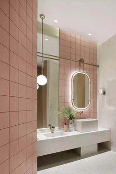 a bathroom with pink tile walls and white counter tops, two sinks and a mirror on the wall