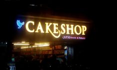 a cake shop sign lit up at night