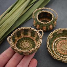 three small baskets sitting on top of a table next to some green leaves and grass