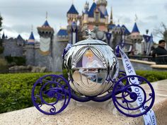 a silver ball sitting on top of a stone wall in front of a disney castle