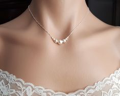 a woman wearing a necklace with three pearls on it's neck, in front of a mannequin