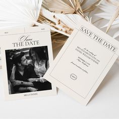 two save the dates cards sitting next to each other on top of a white table