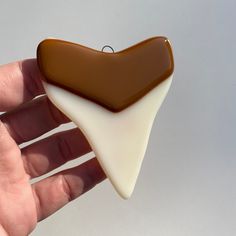 a hand is holding a piece of chocolate and white icing that looks like a heart