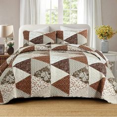 a bed covered in a brown and white quilted comforter next to a window