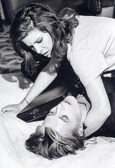 black and white photograph of two women laying on the bed with one holding an object in her hand