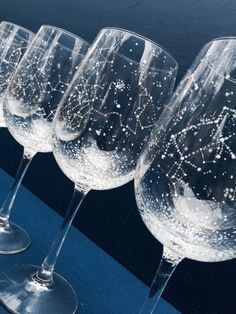 five wine glasses are lined up next to each other on a blue tableclothed surface