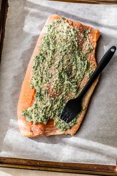 a piece of salmon covered in pesto and parsley on top of parchment paper