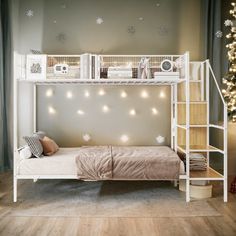 a white bunk bed sitting next to a christmas tree with lights on the bottom shelf