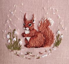 an embroidered squirrel sitting in the grass with snowdrops on it's back