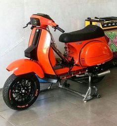 an orange scooter parked next to a wall