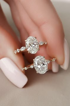 a woman's hand holding two diamond engagement rings