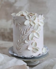 a close up of a cake on a plate with white frosting and flower decorations