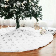 a small christmas tree sitting on top of a wooden floor next to a white blanket