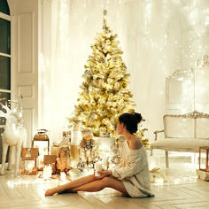 a woman sitting on the floor in front of a christmas tree