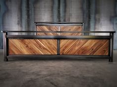 two wooden dressers sitting next to each other in front of a metal wall and concrete floor