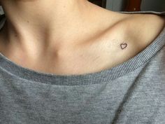 a woman with a small heart tattoo on her chest