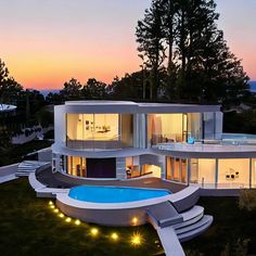 an aerial view of a modern house with pool at dusk in the foreground and trees on the other side