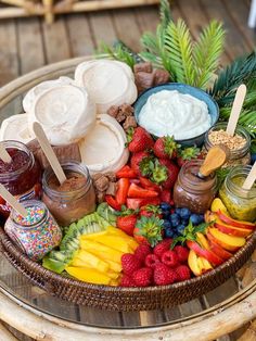 a basket filled with lots of different types of fruit and dips on top of a wooden table