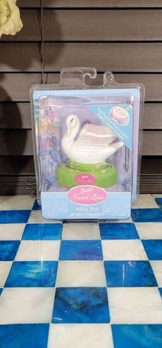 a white swan in a plastic package on a blue and white checkered tile floor