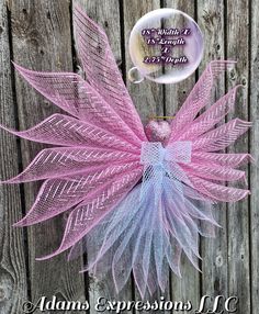 a pink and blue mesh angel decoration on a wooden fence with the words, i believe it's earth day