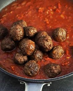 meatballs and tomato sauce in a skillet on the stove top, ready to be cooked