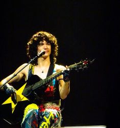 a woman holding a guitar and singing into a microphone