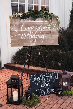 a wooden sign sitting on top of a sidewalk next to a couple of small lanterns