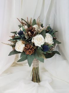 a bridal bouquet with white roses and pine cones