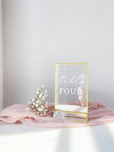 a vase with baby's breath sits next to a clear glass sign that says self four