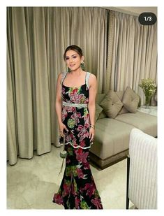 a woman standing in front of a couch wearing a black and pink floral print dress